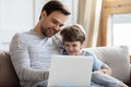 Joyful young father embracing little son, watching movies on laptop. Royalty Free Stock Photo