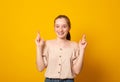 Joyful young female clenches teeth, raises fingers crossed, makes desirable wish, wears casual clothes, waits for good news Royalty Free Stock Photo