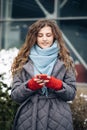 Joyful young female in good mood typing and scrolling on smartphone outdoors. Curly-haired female using smartphone