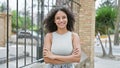 Joyful young hispanic woman flaunting her beautiful curly hair and infectious smile, standing outside in the heart of the city, Royalty Free Stock Photo