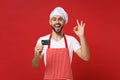 Joyful young male chef cook or baker man in striped apron white t-shirt toque chefs hat isolated on red background Royalty Free Stock Photo