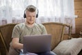 Joyful young man in headphones works with laptop in country house