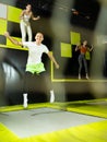 Joyful young man jumping on trampolines in colorful amusement park