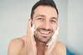 Joyful young man putting shaving soap on his cheeks Royalty Free Stock Photo