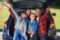 Happy stylish parents with their cute lovely children are making funny selfie on smart phone while sitting in the trunk Royalty Free Stock Photo