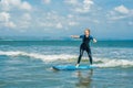 Joyful young woman beginner surfer with blue surf has fun on small sea waves. Active family lifestyle, people outdoor