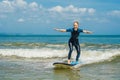 Joyful young woman beginner surfer with blue surf has fun on small sea waves. Active family lifestyle, people outdoor