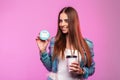 Joyful young woman with cup hot tea with sweet smile in fashionable blue jeans clothing smiles and hold in hand donut in face mask Royalty Free Stock Photo