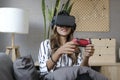 Joyful young woman holding joystick console playing video games on virtual reality headset. Futuristic environment, leisure