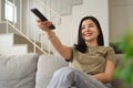 Joyful young woman holding remote control, watching television on comfortable sofa at home Royalty Free Stock Photo