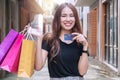 Joyful woman holding shopping bags and blank credit card on city street background with copy space. Happiness, consumer, Royalty Free Stock Photo