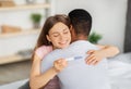 Joyful young woman hugging her black husband, holding positive pregnancy test at home Royalty Free Stock Photo