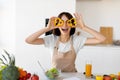 Joyful young woman making glasses of sweet pepper, having fun and playing with food while cooking fresh salad in kitchen Royalty Free Stock Photo