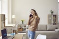 Joyful young woman receives good news during pleasant conversation on mobile phone at home. Royalty Free Stock Photo