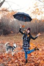 Joyful young woman throwing leaves and playing with her dog in the autumn park Royalty Free Stock Photo