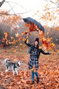 Joyful young woman throwing leaves and playing with her dog in the park Royalty Free Stock Photo