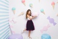 Joyful young woman in tulle skirt having fun with big macaron on white background among sweets. Pastel colors, ice cream Royalty Free Stock Photo