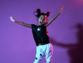 Joyfull asian kid girl in shirt and pants with stars on purple background throws hands up like a winner dancing