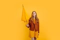 Beautiful girl, in a bright yellow dress and autumn jacket, stands with a yellow umbrella on an  yellow background, Royalty Free Stock Photo
