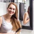 Joyous beautiful young woman standing, brushing her long dry hair Royalty Free Stock Photo