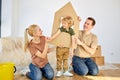 Joyous family and kid boy playing in new home with cardboard boxes on floor. Portrait Royalty Free Stock Photo