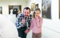 Joyous father and daughter regarding paintings in museum