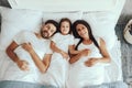 Joyous father enjoying morning in bed with wife and daughter