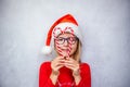 Happy little girl in eye glasses and Santa hat making heart shape with candy canes, Christmas child Ophthalmology