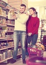 Joyous young couple choosing purchasing canned food for week at Royalty Free Stock Photo