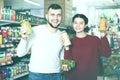 Joyous young family choosing purchasing canned food for week at Royalty Free Stock Photo