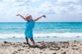 Joyous young girl with hands up relaxing on sandy beach