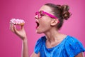 Joyous young woman eating sprinkled doughnut