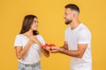 A joyous young woman looks at a smiling man who is giving her a small gift box Royalty Free Stock Photo