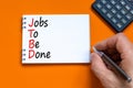 JTBD jobs to be done symbol. Concept words JTBD jobs to be done on white note on a beautiful orange background. Businessman hand.