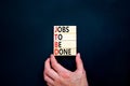 JTBD jobs to be done symbol. Concept words JTBD jobs to be done on wooden blocks on beautiful black background. Businessman hand.