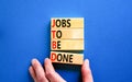 JTBD jobs to be done symbol. Concept words JTBD jobs to be done on wooden blocks on beautiful blue background. Businessman hand.