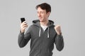 Smiling Guy watching smart phone isolated on gray background