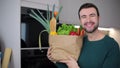 Jubilant man giving a thumbs up while holding his groceries