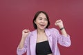 A jubilant short-haired young asian woman celebrating success. Giddy with joy. Studio shot with burgundy background