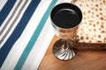 Judaism and religious jewish holiday with matzos unleavened flatbread, cup of wine, and a white and blue tallit, set up for