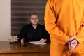 Judge in courtroom looking at prisoner in orange uniform Royalty Free Stock Photo
