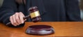 Judge female hand hold a gavel on law court bench, overhead. Justice and punishment concept