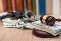 Judge gavel with dollars, books on wooden