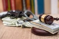 Judge gavel with dollars, books on wooden desk