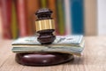 Judge gavel with dollars, books on wooden desk