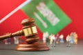 Judge gavel, flag and plastic toy men on red background, Saudi Arabia litigation concept
