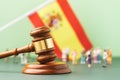 Judge gavel, flag of Spain and plastic toy men on a colored background, the concept of trials in the Spanish society