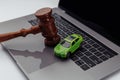 Judge gavel and green toy car on laptop computer keyboard. Symbol of law, justice and online car auction. Royalty Free Stock Photo