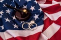 Judge gavel and handcuffs on american flag close up