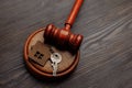 Judge gavel and key chain in shape of two splitted part of house on wooden background. Concept of real estate auction or